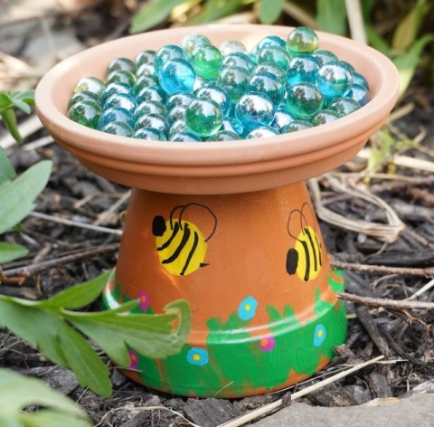 Terracotta pot with the saucer flipped upside down on the base to make a "water bath" for pollinators.